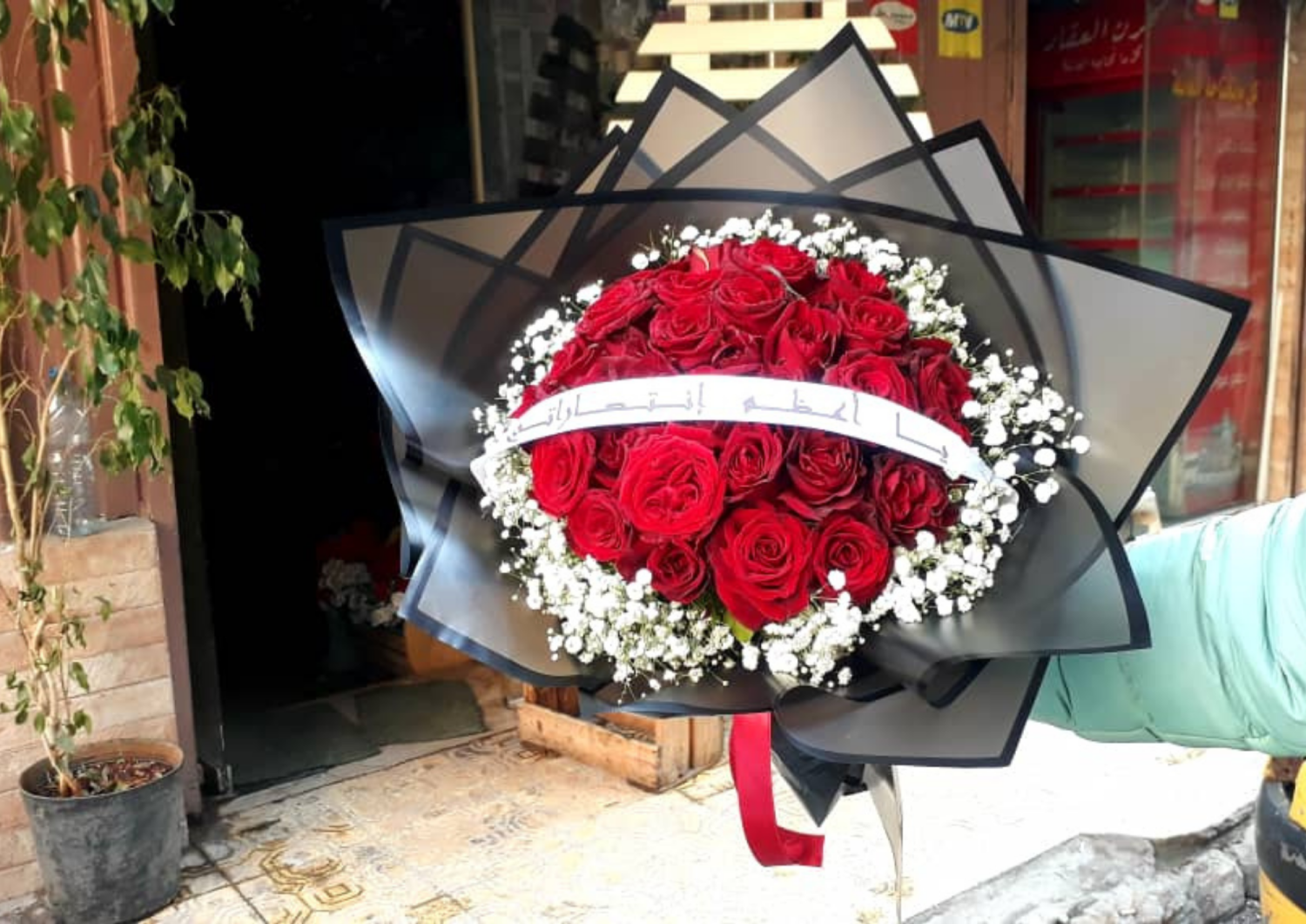 باقة ورد احمر مع شريط عليه كتابة